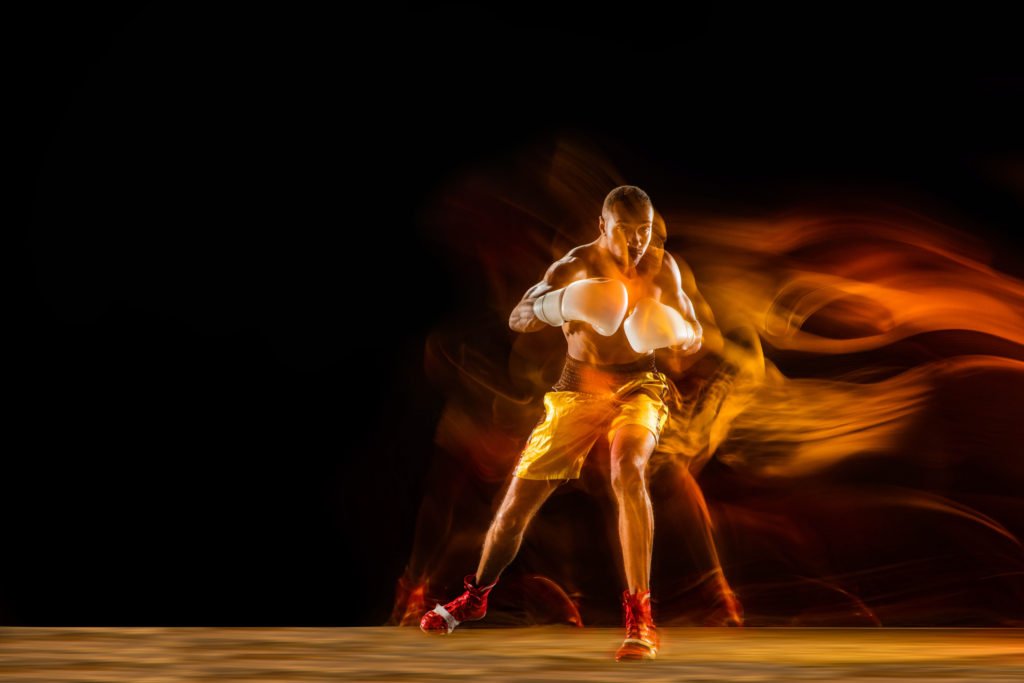 professional boxer training isolated on black studio background in mixed light